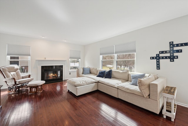 living area featuring a fireplace with flush hearth, baseboards, and dark wood-style flooring