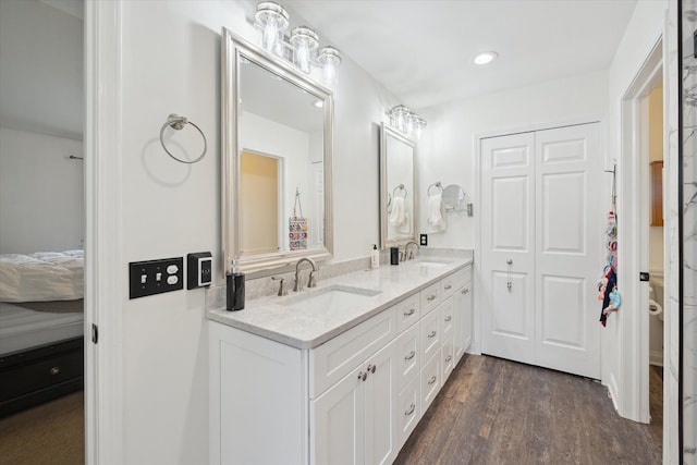 ensuite bathroom with double vanity, wood finished floors, ensuite bathroom, and a sink