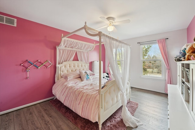 bedroom featuring ceiling fan, visible vents, baseboards, and wood finished floors