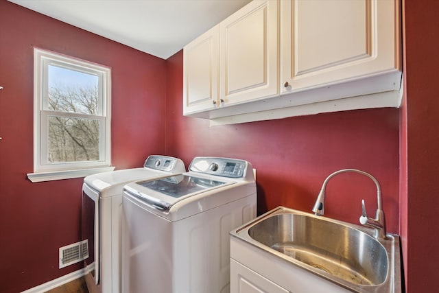 washroom with a sink, visible vents, cabinet space, and washer and clothes dryer