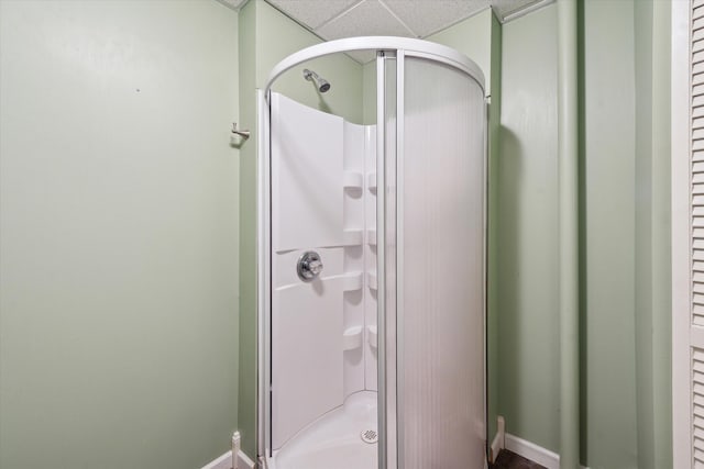 full bath featuring a drop ceiling, baseboards, and a stall shower