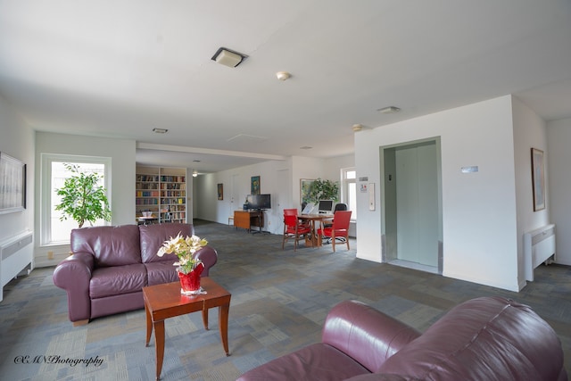 carpeted living room with radiator heating unit and elevator