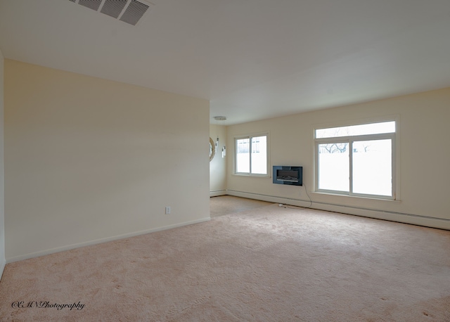 unfurnished living room featuring carpet, visible vents, a wall unit AC, and baseboards