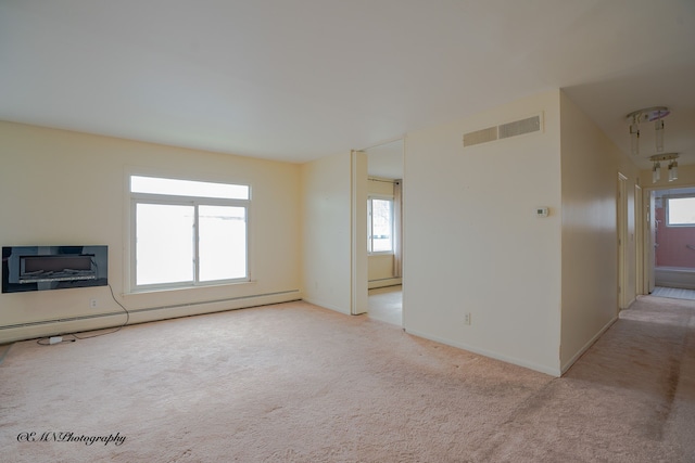 unfurnished living room featuring a healthy amount of sunlight, a baseboard radiator, visible vents, and light colored carpet