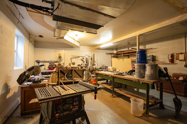 interior space featuring a workshop area, a baseboard radiator, and concrete block wall