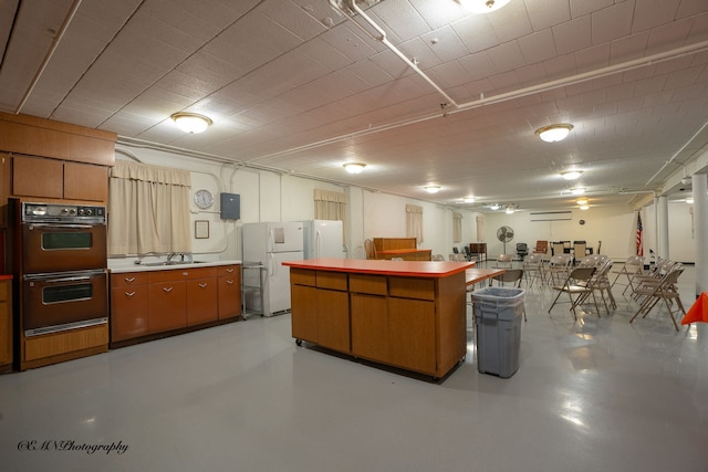 kitchen featuring freestanding refrigerator, a sink, concrete floors, and double wall oven