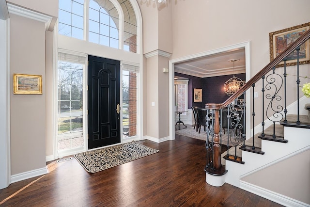 foyer with baseboards, stairway, wood finished floors, a towering ceiling, and an inviting chandelier