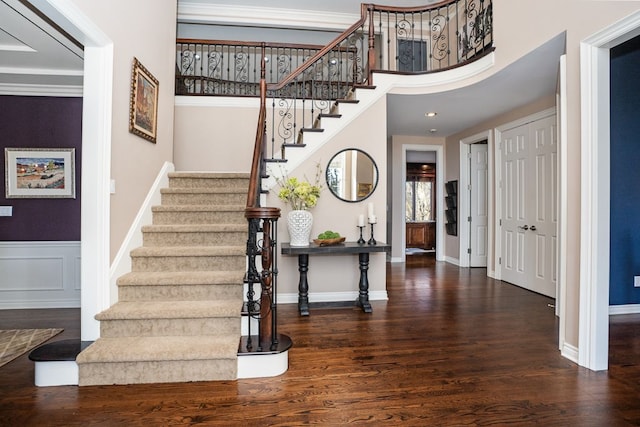 foyer featuring wood finished floors, a wainscoted wall, baseboards, recessed lighting, and stairs