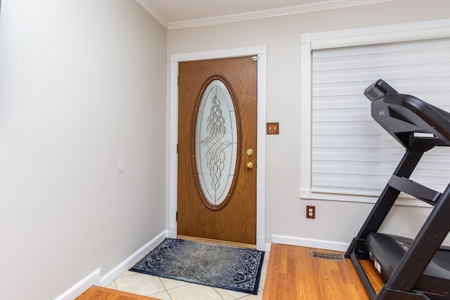 foyer entrance with visible vents, crown molding, baseboards, and wood finished floors