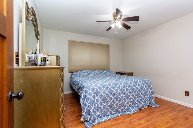 bedroom featuring ceiling fan, baseboards, and wood finished floors