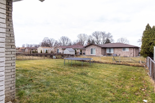 view of yard with a trampoline, a fenced backyard, and a residential view