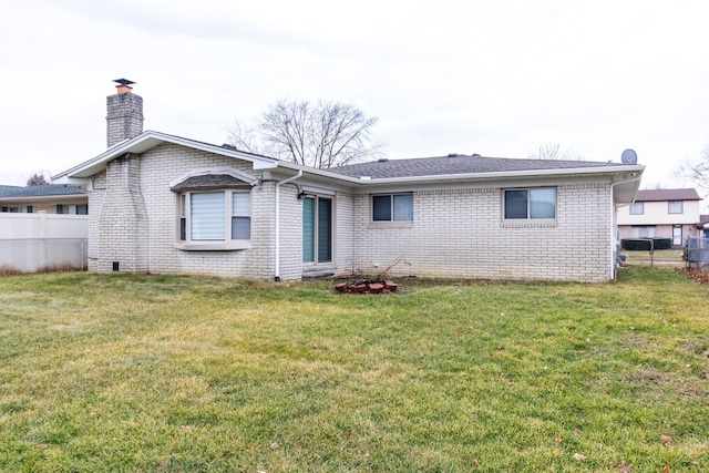 rear view of property with brick siding, a chimney, fence, and a yard