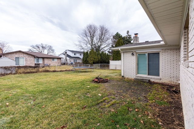 view of yard featuring a trampoline and fence