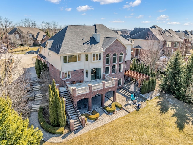 rear view of property featuring brick siding, a lawn, stairs, and a patio area