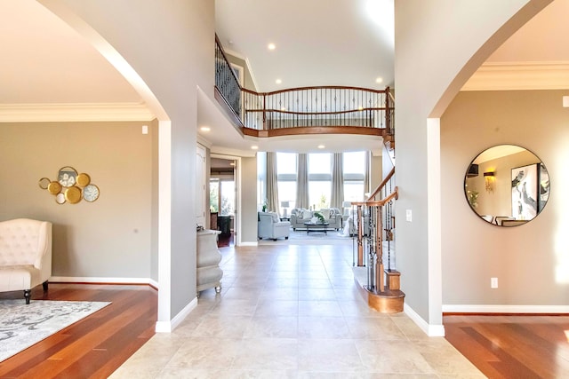 entryway with light wood finished floors, crown molding, and baseboards