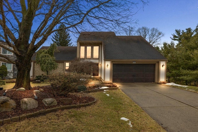 view of front of home with driveway, an attached garage, and a shingled roof