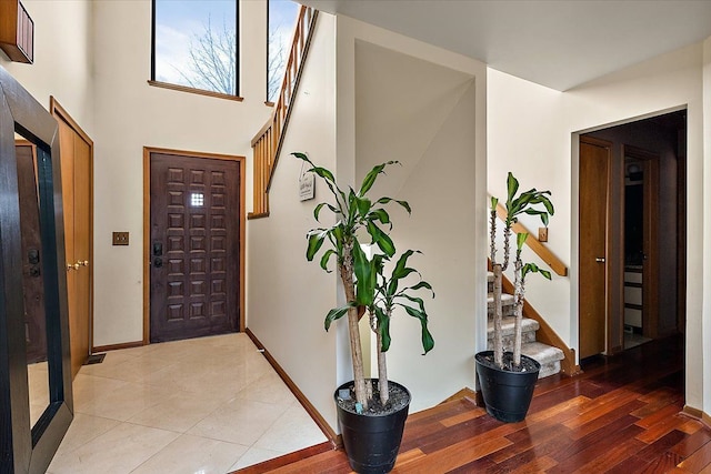 foyer featuring light tile patterned floors, baseboards, and stairs