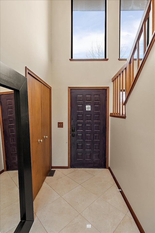 entrance foyer featuring light tile patterned flooring, a high ceiling, and baseboards