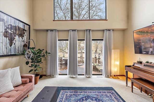 entryway with carpet flooring, baseboards, and a towering ceiling