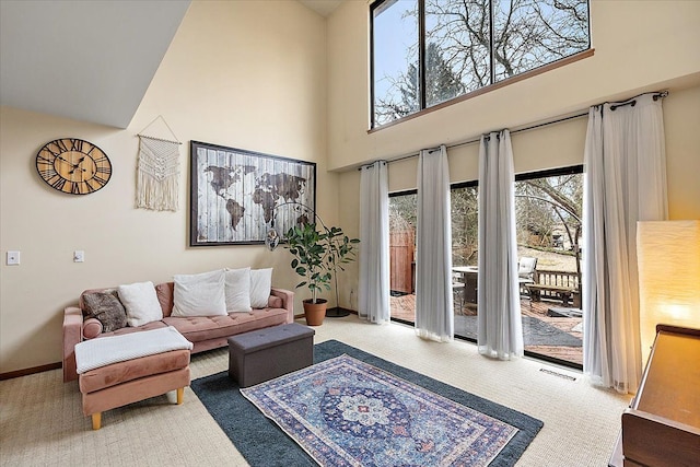 carpeted living room featuring visible vents, baseboards, and a towering ceiling