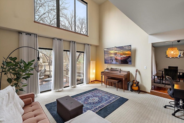 carpeted living area with baseboards and a towering ceiling