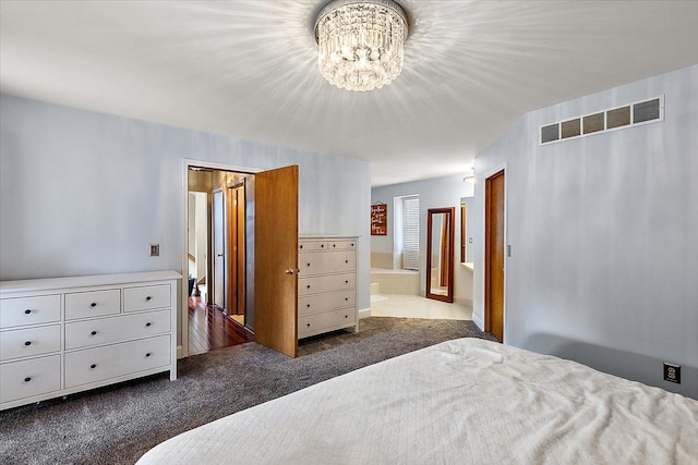 bedroom featuring dark colored carpet, visible vents, ensuite bath, and a chandelier