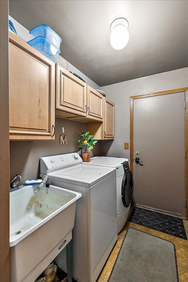 washroom with washer and dryer, cabinet space, and a sink