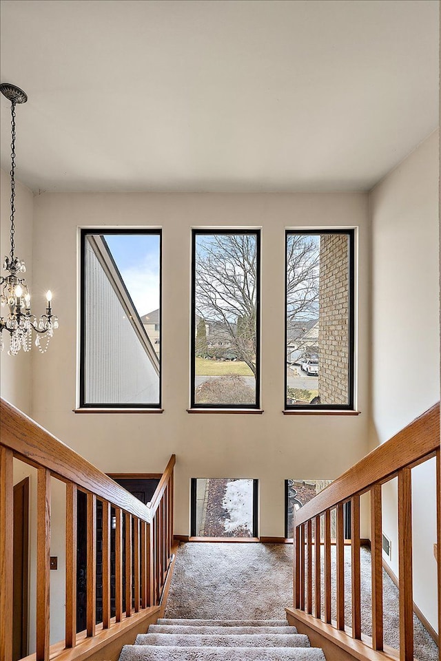 stairway featuring visible vents, an inviting chandelier, and carpet