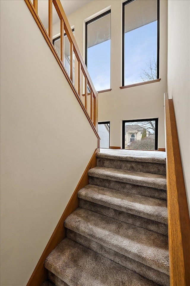 staircase with baseboards and a high ceiling