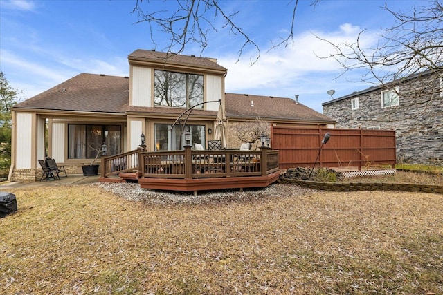 back of house with a wooden deck, a patio, and roof with shingles