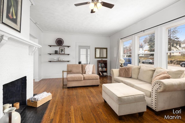 living room featuring a healthy amount of sunlight, hardwood / wood-style flooring, a brick fireplace, and baseboards