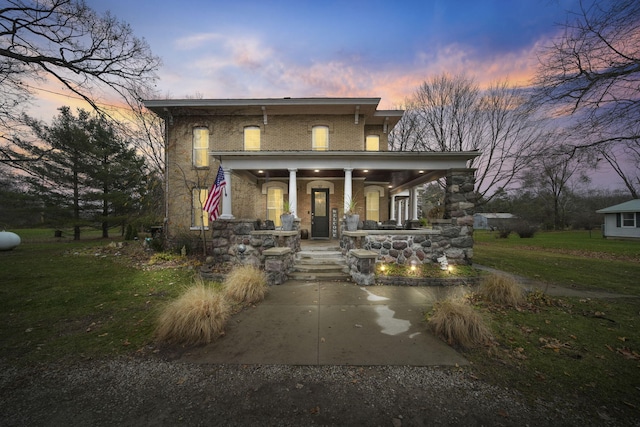 italianate house with covered porch, brick siding, and a front yard