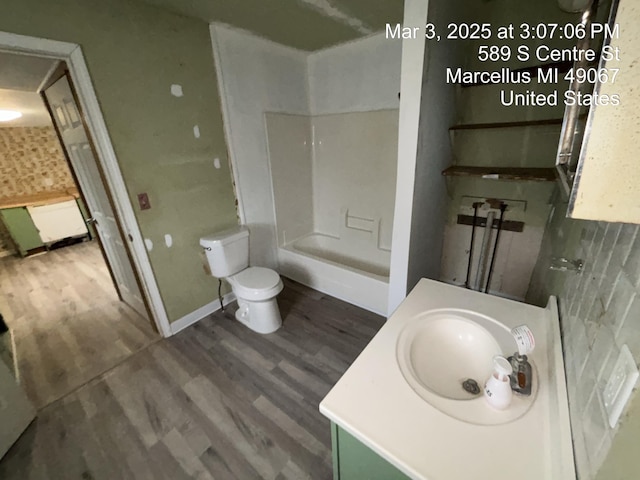 bathroom featuring toilet, baseboards, wood finished floors, and vanity