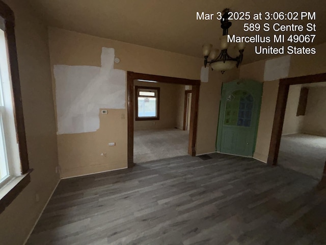 spare room featuring wood finished floors and a notable chandelier