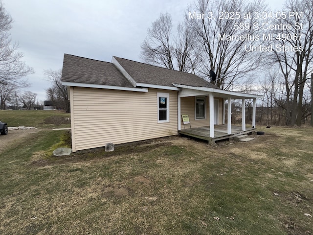 back of property featuring covered porch, roof with shingles, and a lawn