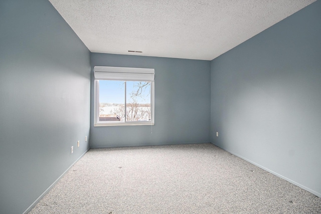 carpeted empty room with a textured ceiling and baseboards