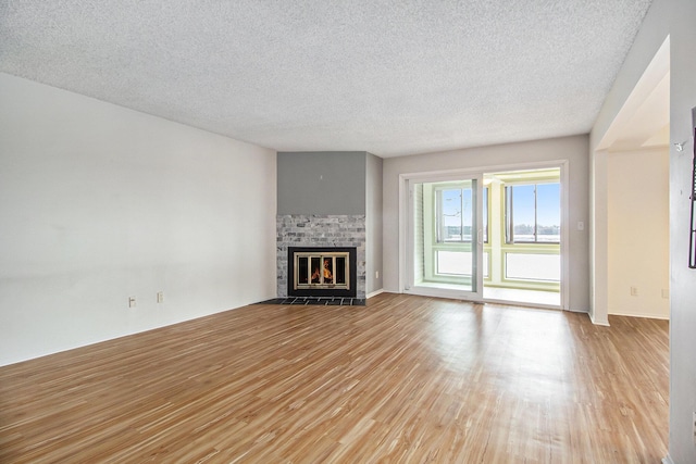 unfurnished living room featuring a textured ceiling, light wood-type flooring, and a fireplace with flush hearth