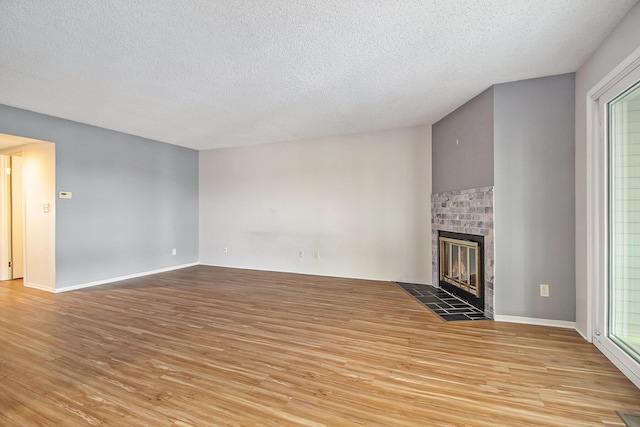 unfurnished living room featuring a brick fireplace, light wood-style flooring, and a textured ceiling