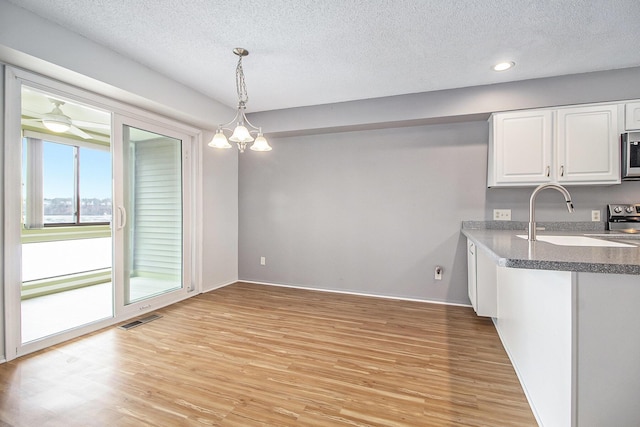 kitchen with light wood-style flooring, a sink, visible vents, white cabinetry, and appliances with stainless steel finishes