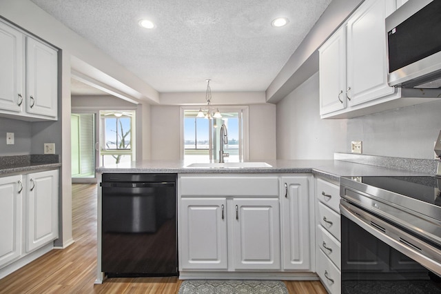 kitchen featuring a peninsula, stainless steel appliances, light wood-type flooring, white cabinetry, and a sink