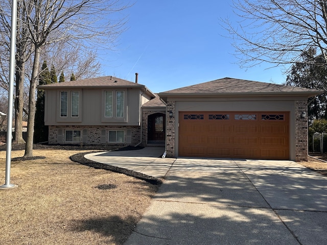 tri-level home with brick siding, driveway, an attached garage, and an outbuilding