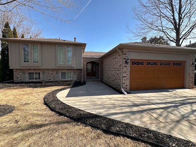 split level home with brick siding, an attached garage, and concrete driveway