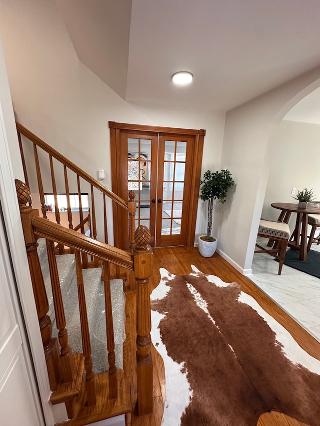 interior space featuring wood finished floors, arched walkways, french doors, and baseboards