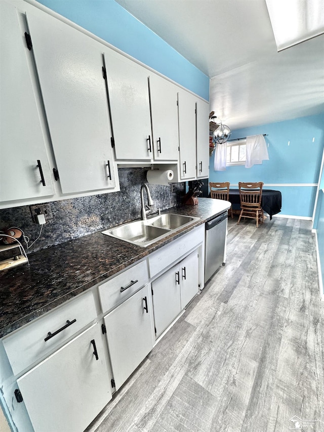 kitchen featuring a sink, white cabinets, stainless steel dishwasher, light wood finished floors, and tasteful backsplash