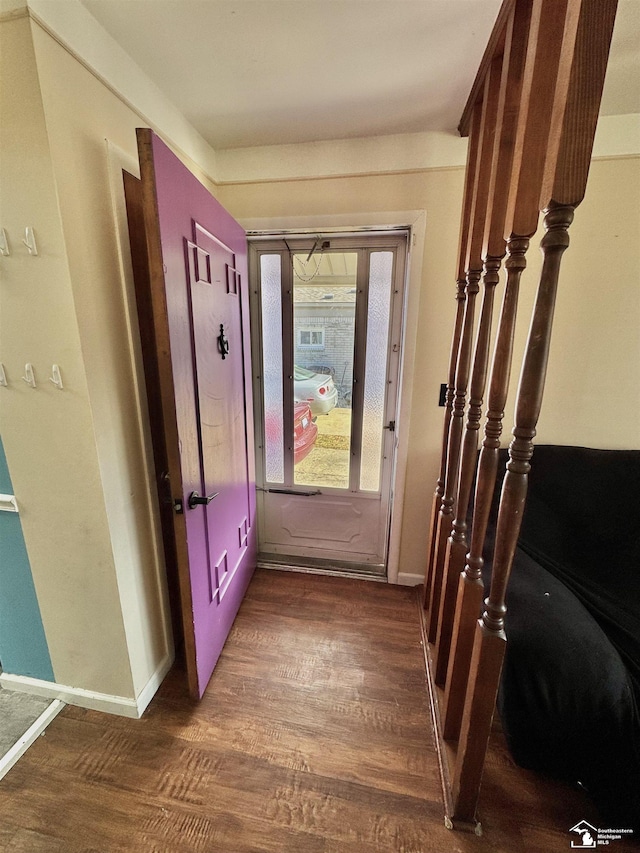 doorway to outside featuring baseboards and dark wood finished floors