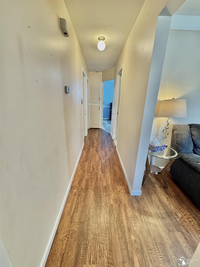 hallway featuring baseboards and wood finished floors