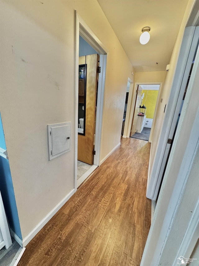 corridor featuring baseboards and wood finished floors