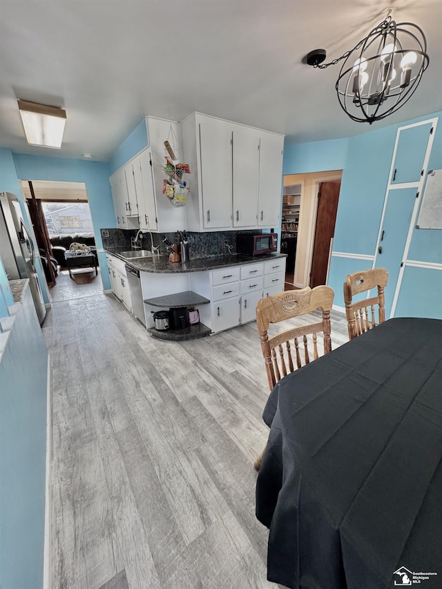 kitchen with appliances with stainless steel finishes, dark countertops, light wood-style floors, and a sink