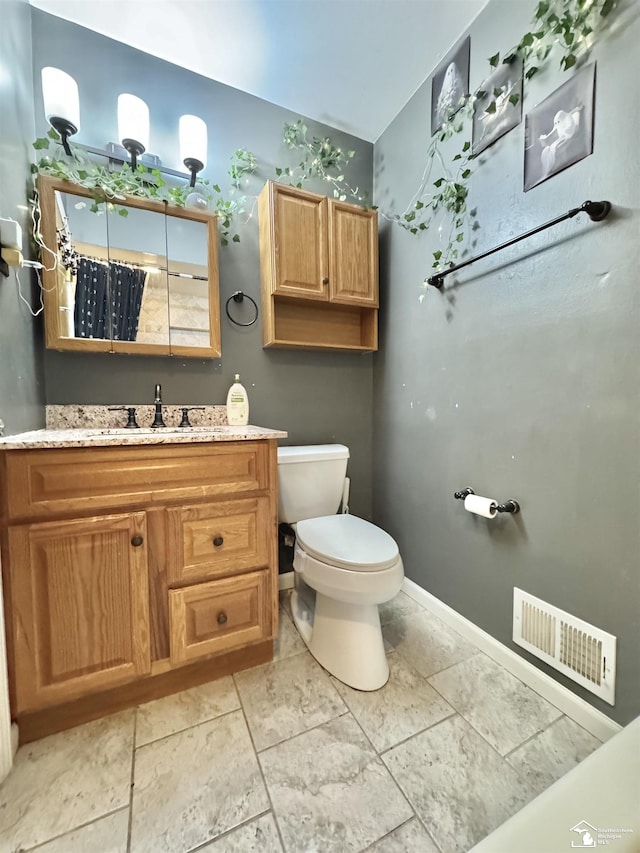 bathroom with toilet, vanity, visible vents, and baseboards