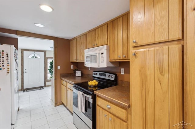 kitchen featuring light tile patterned floors, white appliances, and dark countertops